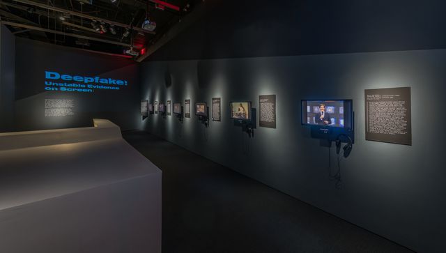 An image of a museum corridor lined with flat video monitors